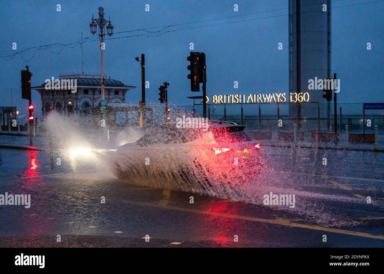 Brighton UK 27. Dezember 2020 - EIN Auto fährt am frühen Morgen durch Überschwemmungen an der Strandpromenade von Brighton, als Sturm Bella Großbritannien heute mit starken Winden und starken Regenfällen schlägt, die Überschwemmungen und Schäden in einigen Gebieten verursachen : Credit Simon Dack / Alamy Live News Stockfoto