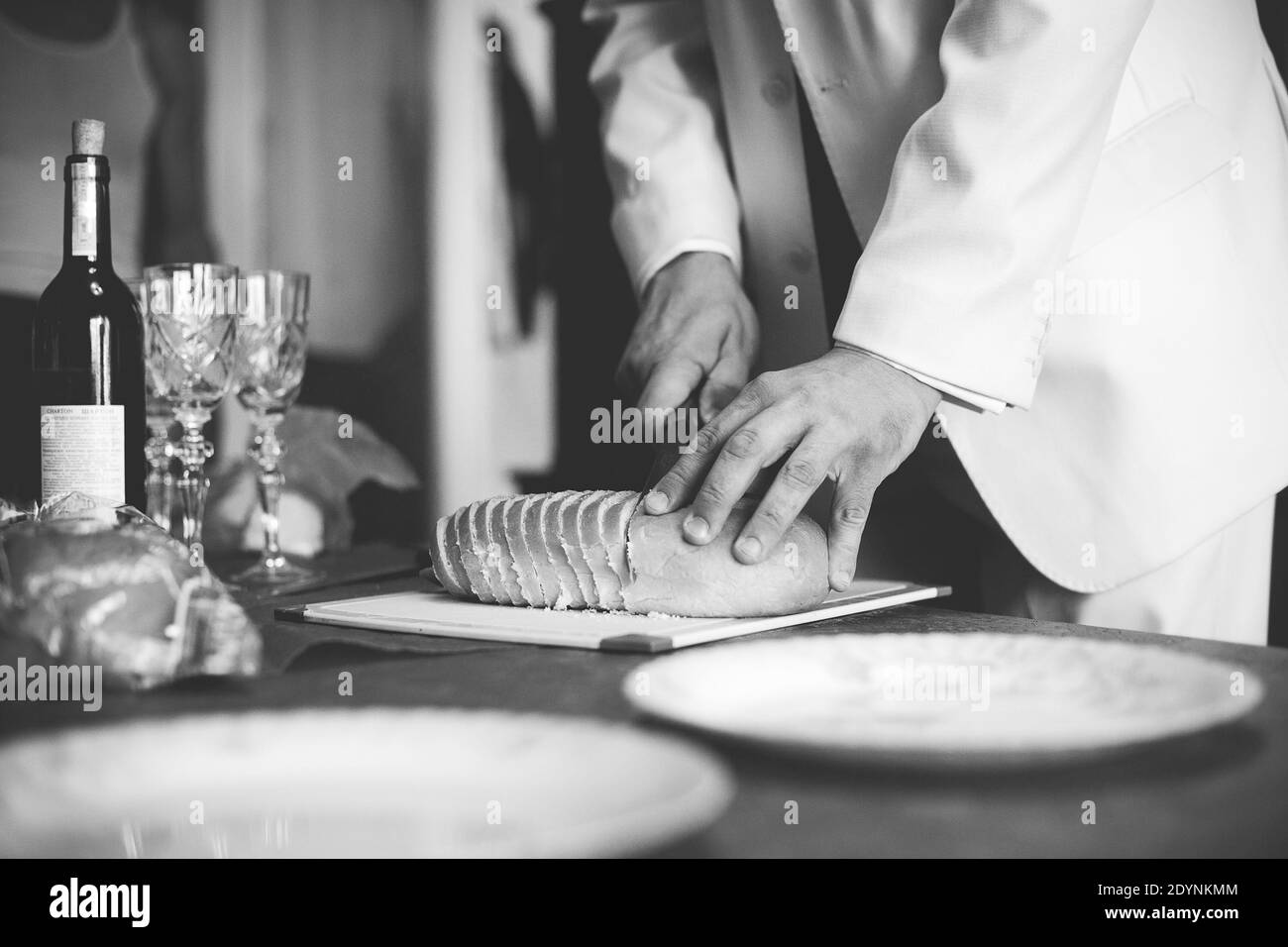 Der Mann schneidet Brot. Festlicher Tisch. Schwarzweiß-Fotografie. Stockfoto