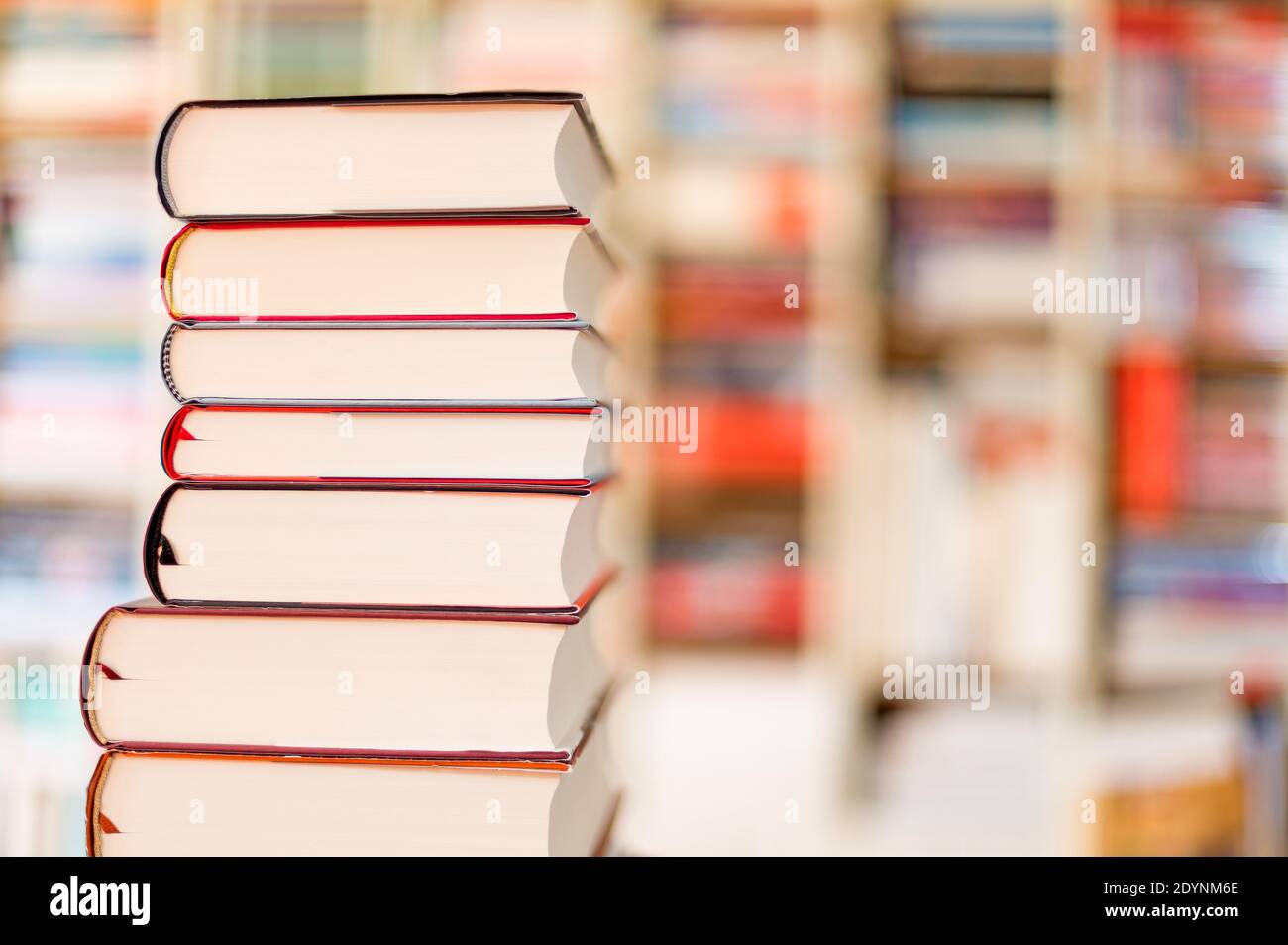 Gestapelte Bücher vor einem Bücherregal Stockfoto