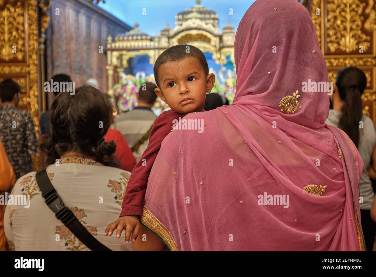 Eine ISKCON ('Hare Krishna')-Anhängerin mit ihrem Kind während der Abendgebete im Sri-Sri-Radha-Gopinath-Tempel, Girgum, Chowpatty, Mumbai, Indien Stockfoto