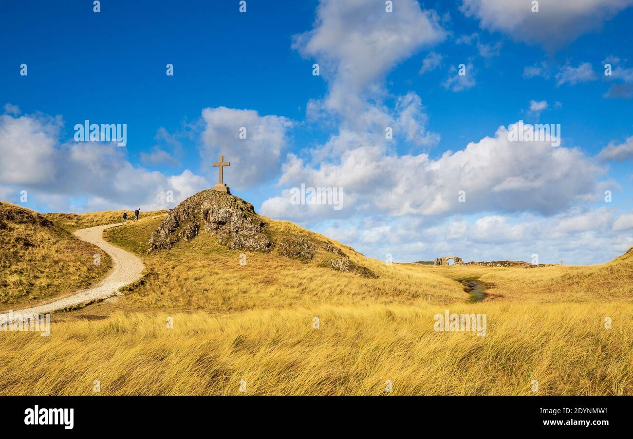 Ein Blick auf den Küstenweg und die Ruinen der St. Dwynwen Kirche und die modernen und keltischen Kreuze auf Llanddwyn Insel, Anglesey Stockfoto