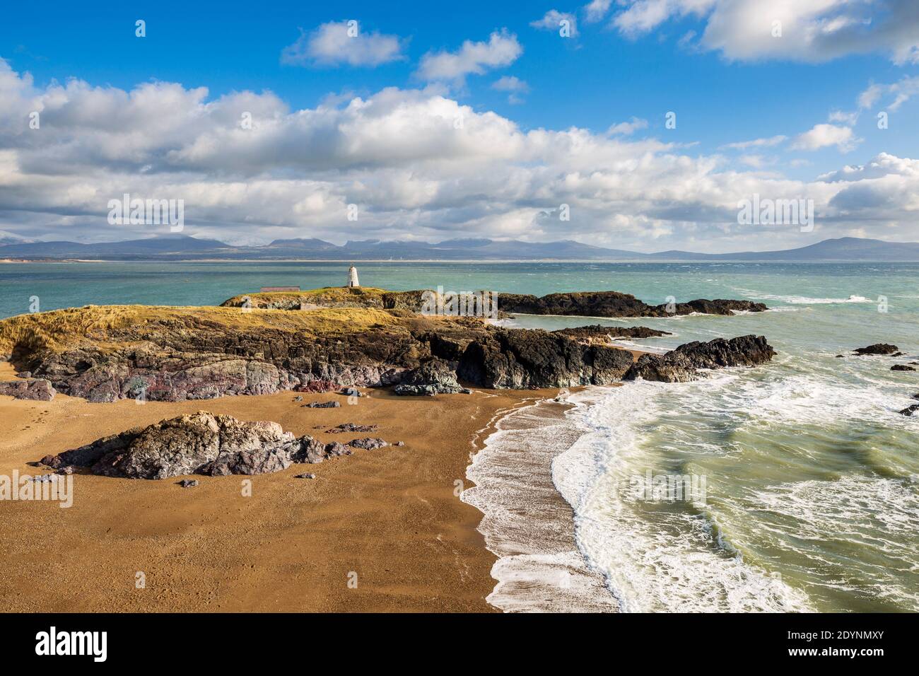 Ein Blick auf Twr Bach und die schneebedeckten Snowdonia Berge über Porth Twr Mawr auf Llanddwyn Island, Anglesey Stockfoto