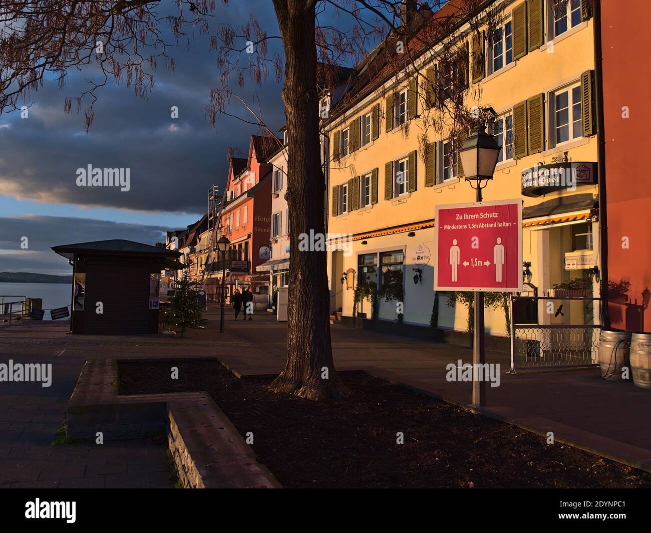 Fast leere Uferpromenade mit geschlossenen Geschäften und Restaurants während der Covid-19 Sperre. Schild: Zu Ihrem Schutz: Bitte halten Sie einen Abstand von 1.5m. Stockfoto