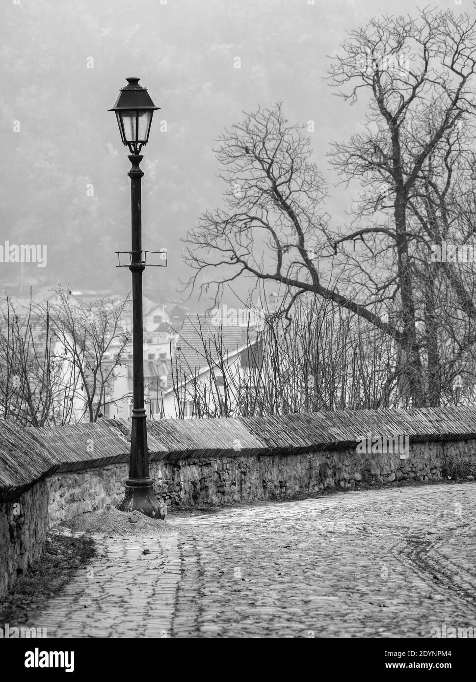 Altes Schwarz-Weiß-Bild einer Straßenlaterne und Die Kopfsteinpflasterstraßen in der mittelalterlichen Zitadelle von Sighisoara Stockfoto