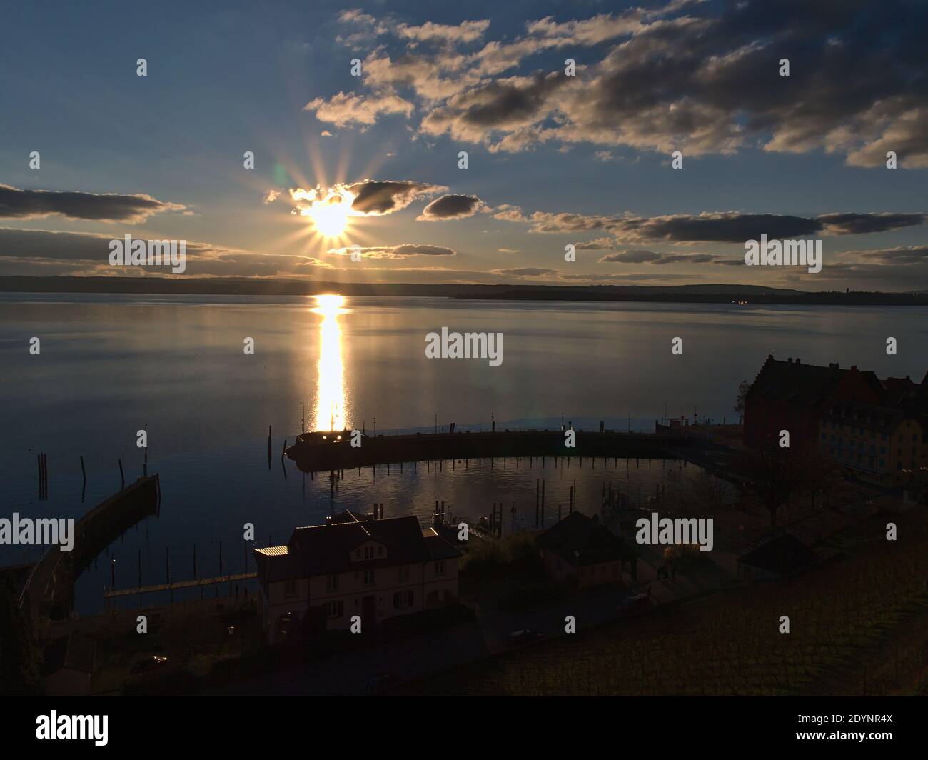 Schöne Aussicht auf Hafenbecken und Pier in Silhouette der Stadt Meersburg, Deutschland am Ufer des Bodensees in Hintergrundbeleuchtung mit heller Abendsonne. Stockfoto