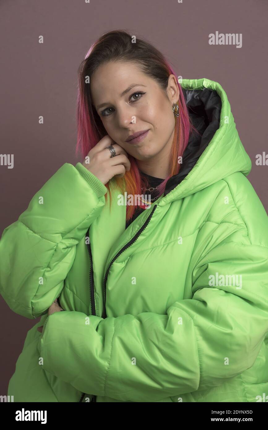 Eine junge Frau mit rosa Haaren, die einen grünen Kugelfisch trägt Jacke Stockfoto