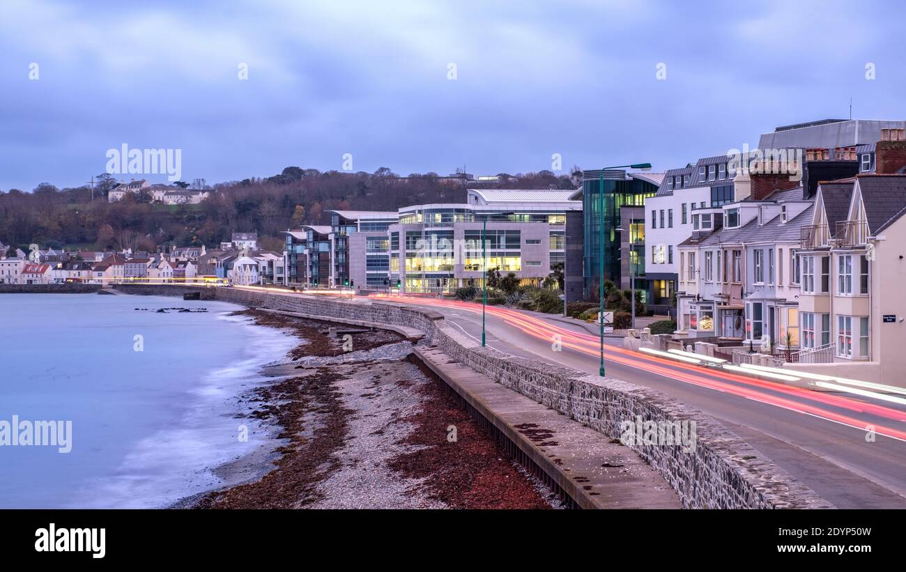 Am Abend pendeln Sie an der Ostküste von Guernsey entlang, vorbei an einem Finanzzentrum Stockfoto
