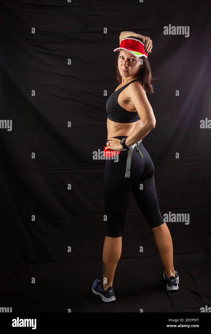 Schöne rothaarige Mädchen in Jogging Uniform posiert im Studio auf schwarzem Hintergrund. Stockfoto