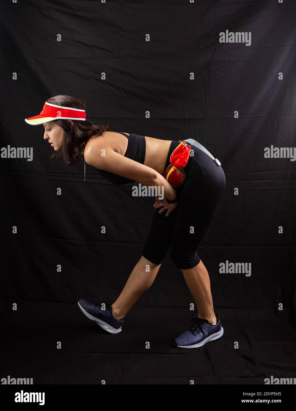 Schönes Mädchen in einer Jogging roten Uniform Aufwärmen vor dem Training im Studio auf einem schwarzen Hintergrund. Stockfoto