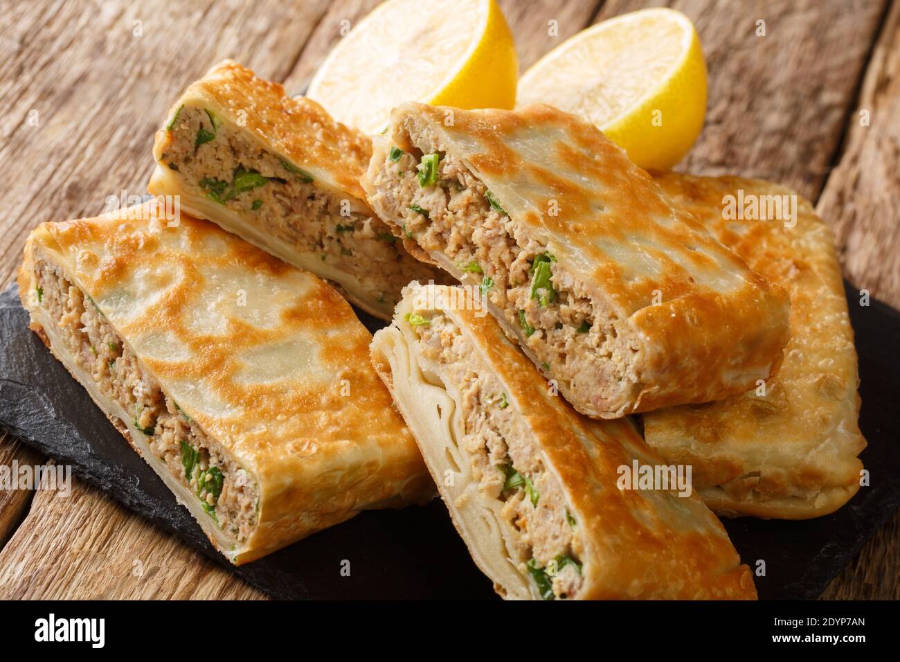 Mutabbaq ist ein arabisches Brot mit Ei und würzigen Fleischfüllung in der Nähe in das Brett auf dem Tisch. Horizontal Stockfoto