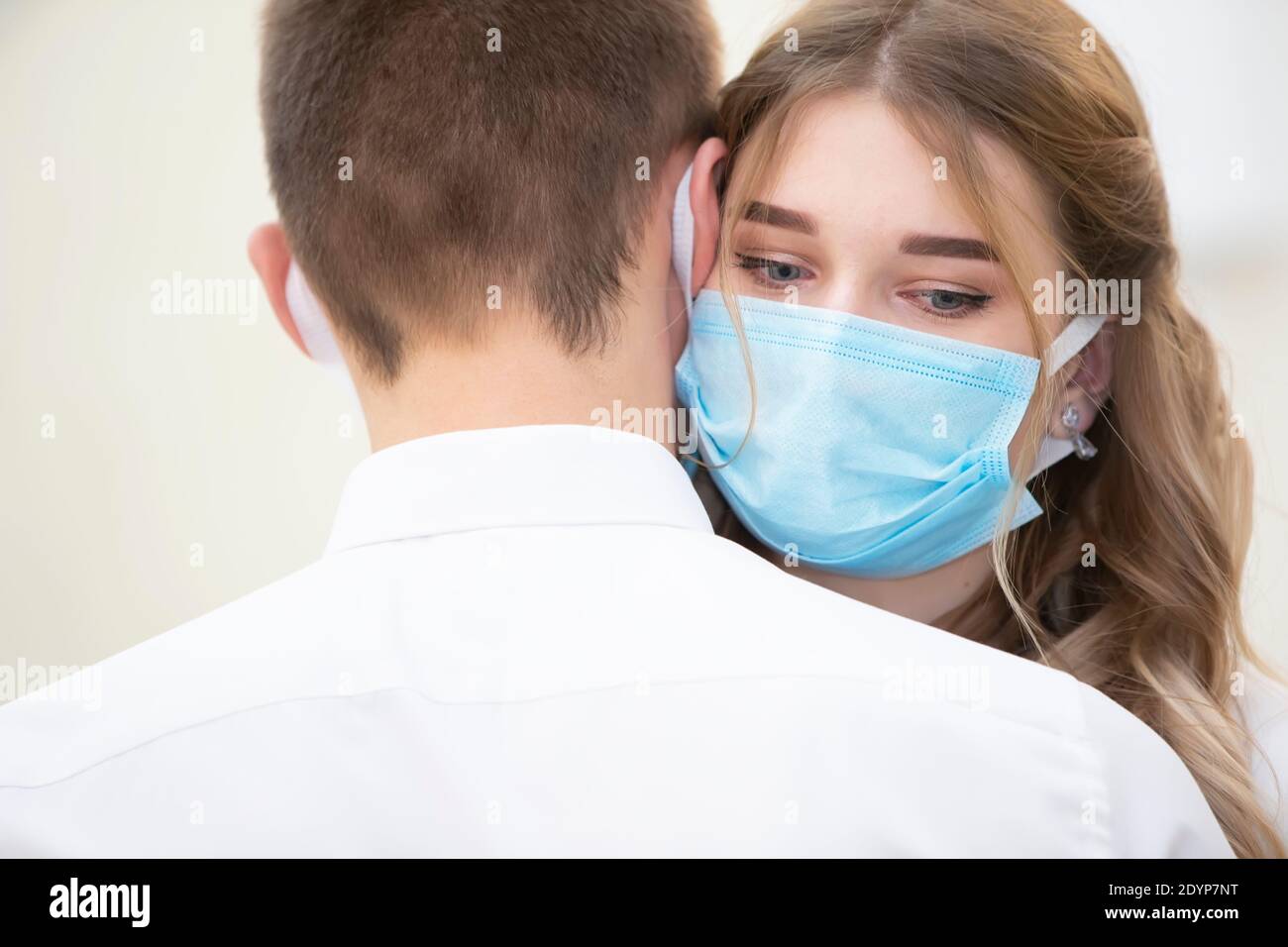 Die Braut in einer medizinischen Maske mit einem Blumenstrauß tanzt mit dem Bräutigam. Hochzeit während der Coronavirus panademia. Stockfoto