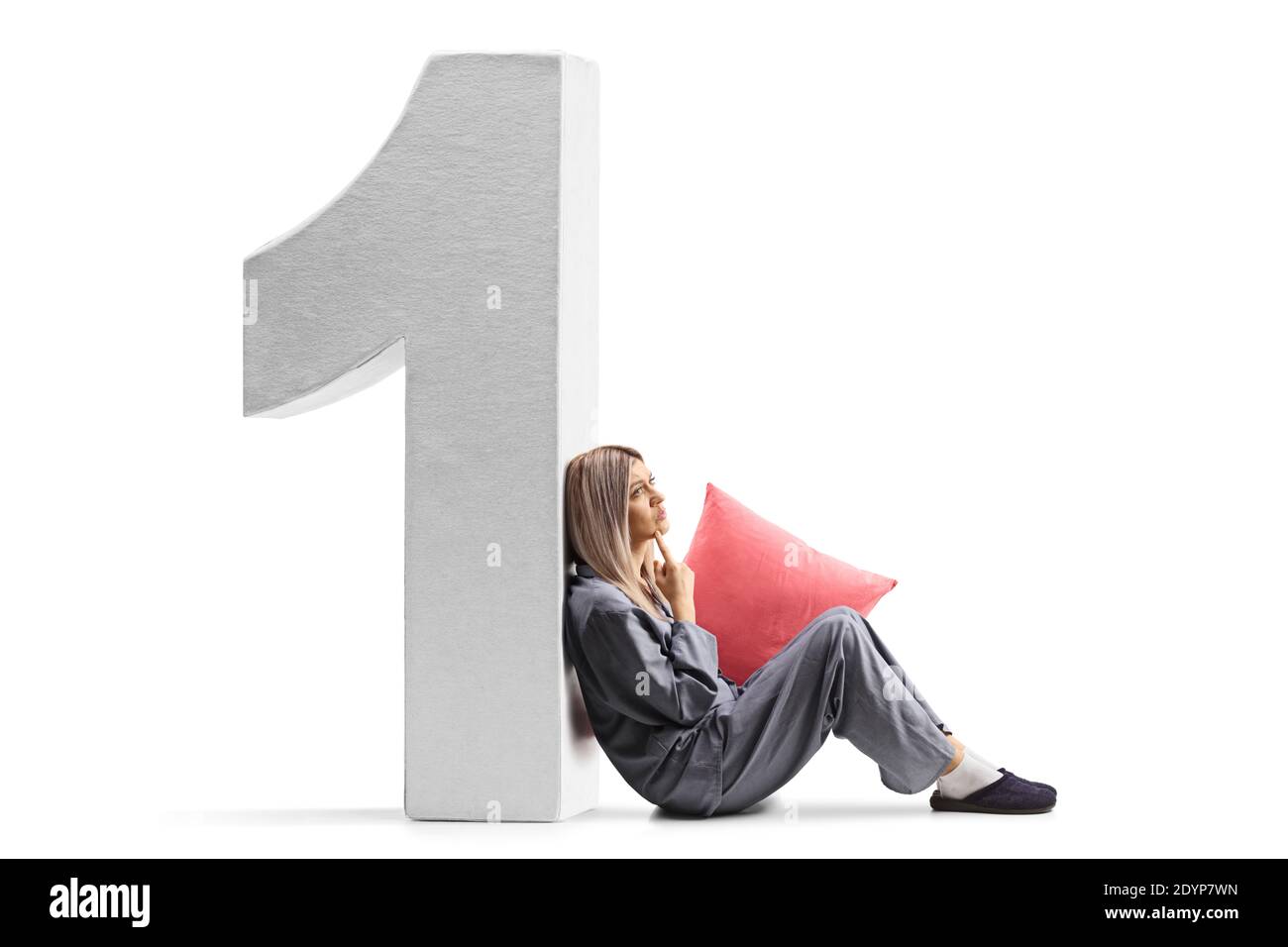 Nachdenkliche Frau im Schlafanzug sitzt auf dem Boden und lehnt sich an Nummer eins isoliert auf weißem Hintergrund Stockfoto
