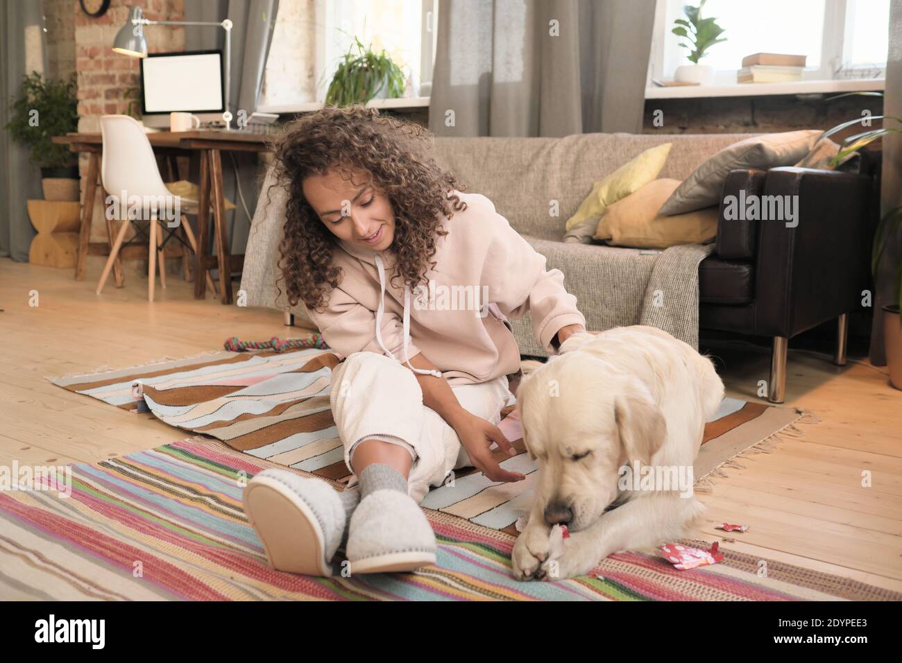 Junge glückliche Frau auf dem Boden sitzen und spielen mit Ihr Haustier im Zimmer Stockfoto
