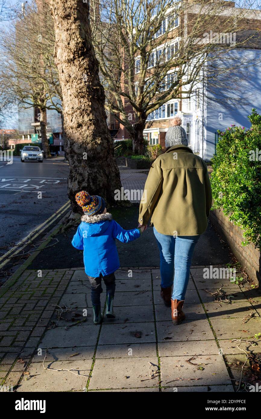 Eine Mutter und ein Sohn, die zusammen die Hände im Winter halten Kleidung Stockfoto