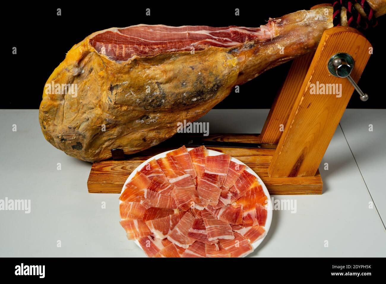 Detail des Schinkens in einem Holzschinkenhalter bereit geschnitten werden. Exquisites Essen. Spanische Tradition. Beschickungskonzept Stockfoto