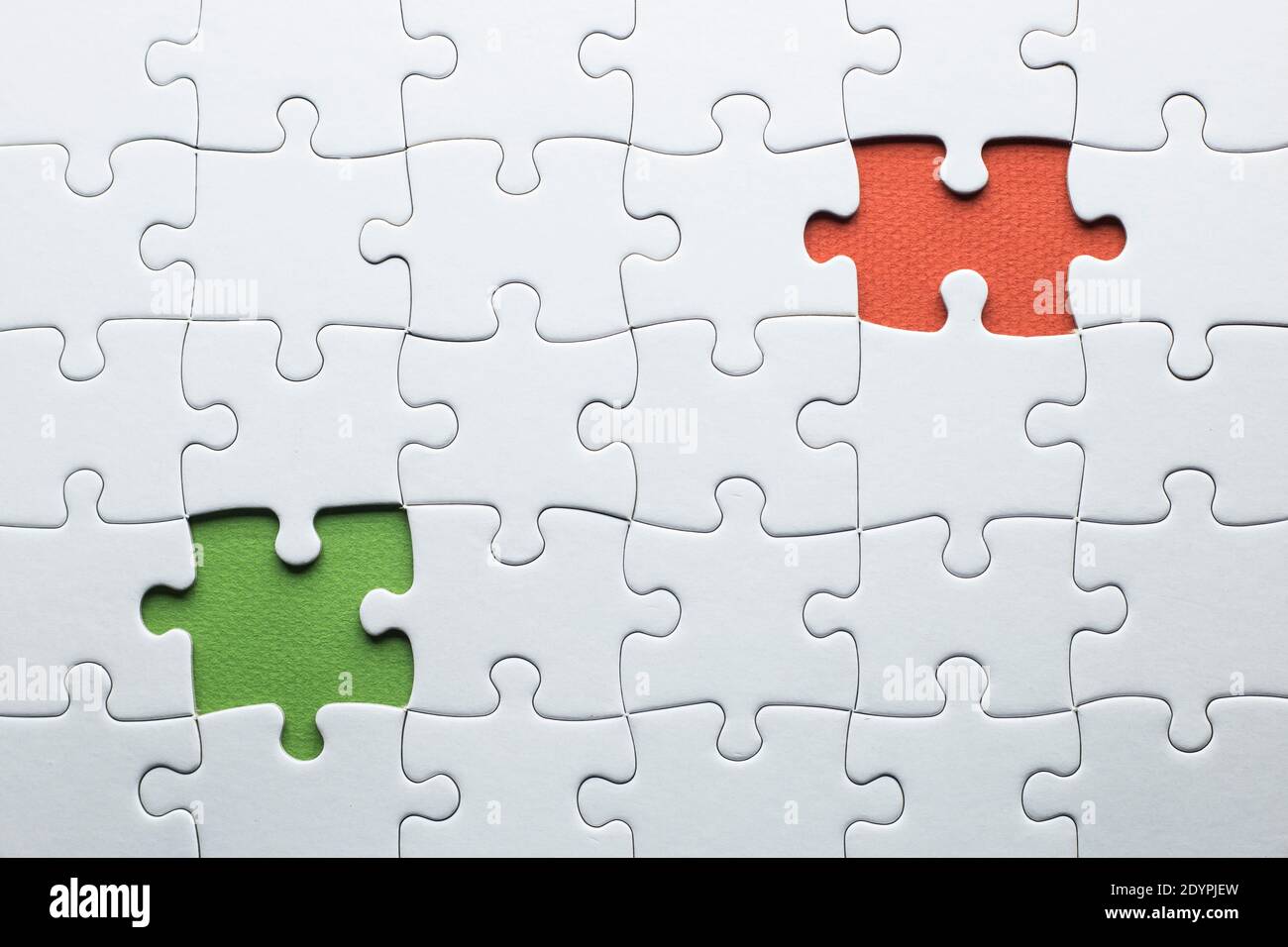 Ein Puzzle fehlt zwei Stücke in verschiedenen Farben abgeschlossen werden. Weiße Stücke und ein Stück in grün und ein in orange Text hinzuzufügen Stockfoto
