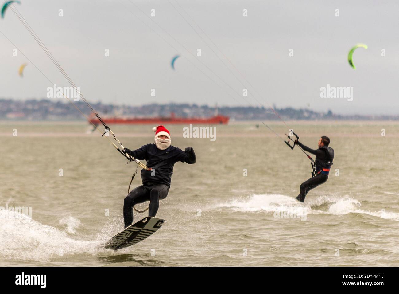 Kitesurfen am Boxing Day in Southend on Sea, Essex, Großbritannien. Männlicher Kite-Surfer trägt festlichen Weihnachtsmann Hut und weißen Bart, Springen aus dem Wasser Stockfoto