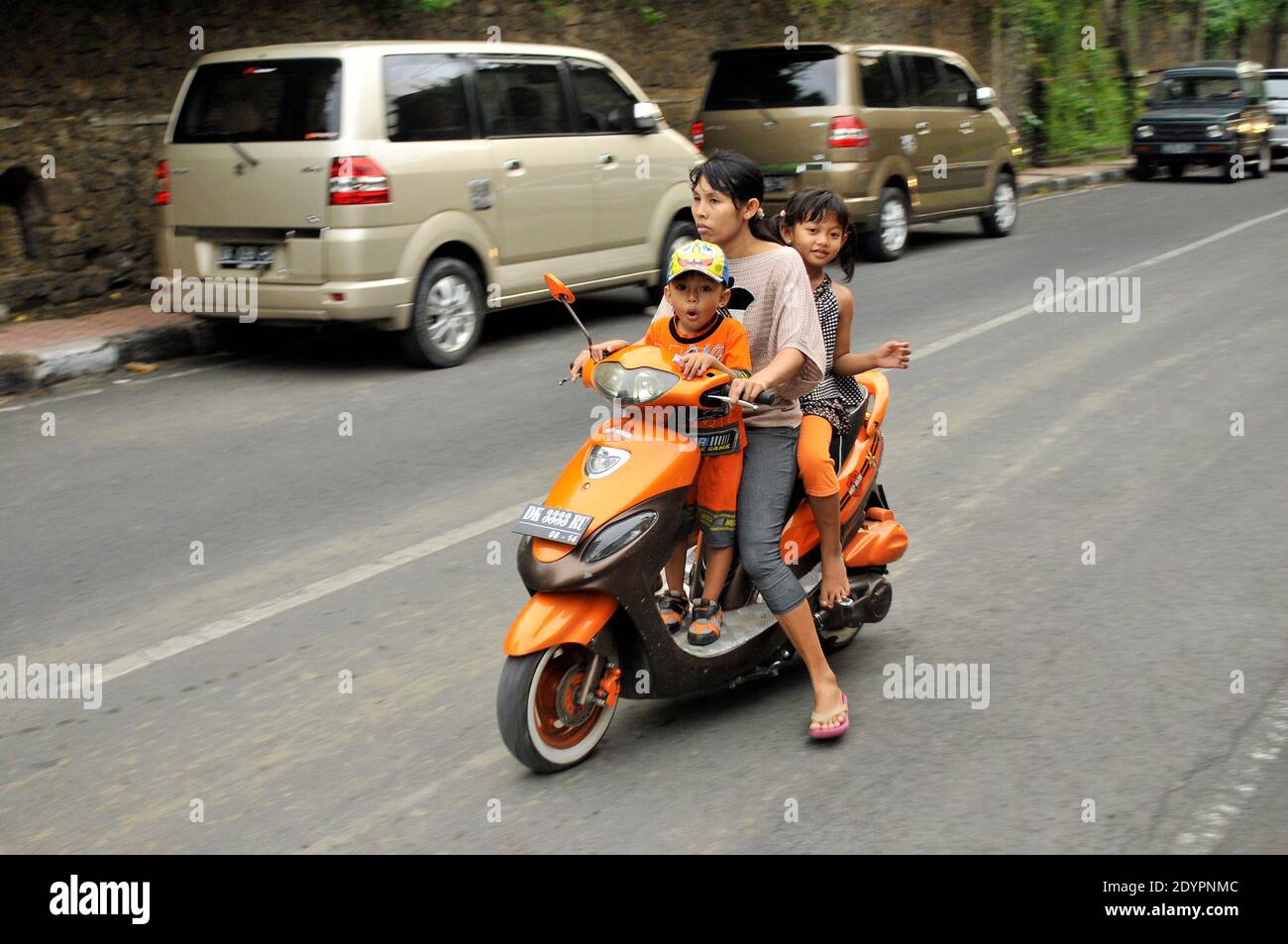 Eine balinesische Mutter und ihre beiden Kinder auf einem Moped. Stockfoto