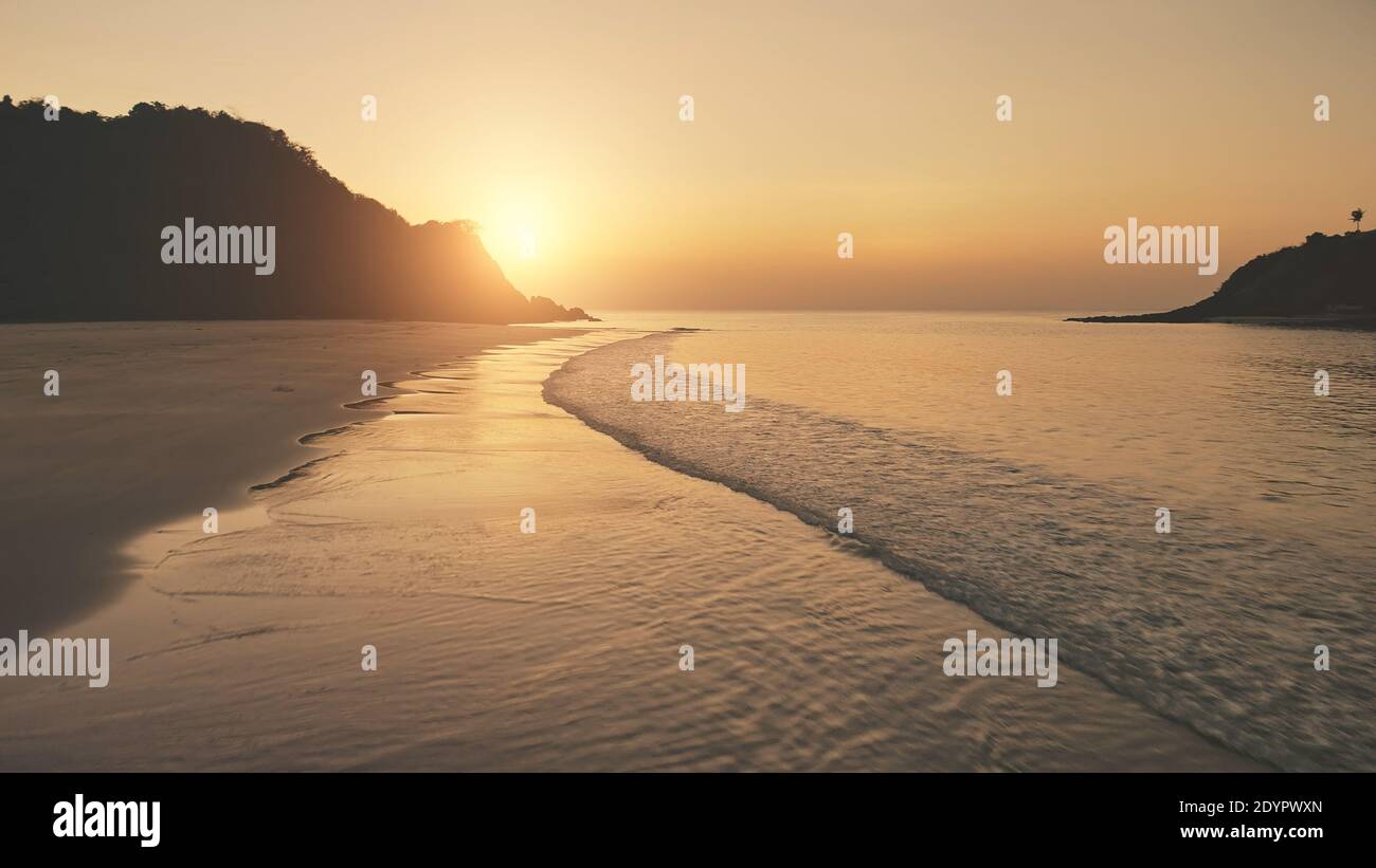 Sonnenuntergang über den Wellen des Ozeans waschen Sandstrand. Luftsonne unterging über Berg Silhouette. Tropic niemand Natur Seestück. Paradiesinsel El Nido, Philippinen, Asien an der Meeresbucht Stockfoto