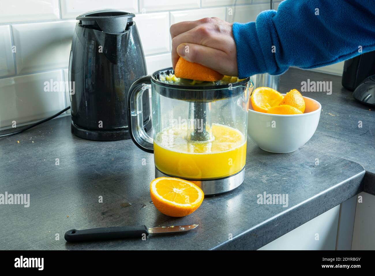 Person ist die Herstellung von Saft aus frischen Orangen mit und elektrisch Quetschpresse oder Entsafter Stockfoto