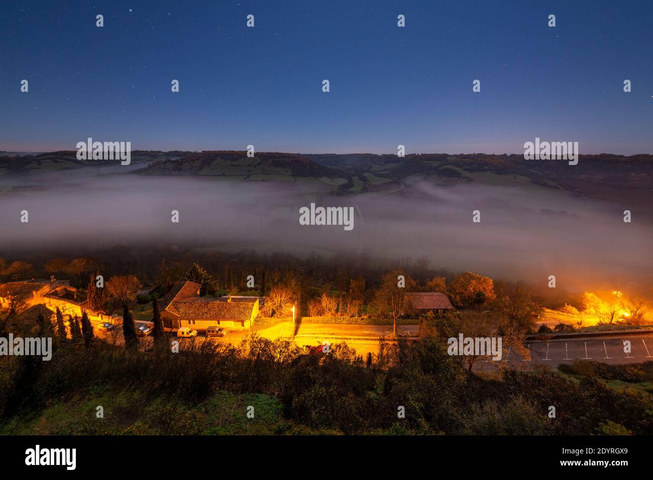 Ein nebeliges französisches Tal, in dem Dorf Cordes-sur-Ciel, das nur bei Mondlicht fotografiert wurde. Stockfoto