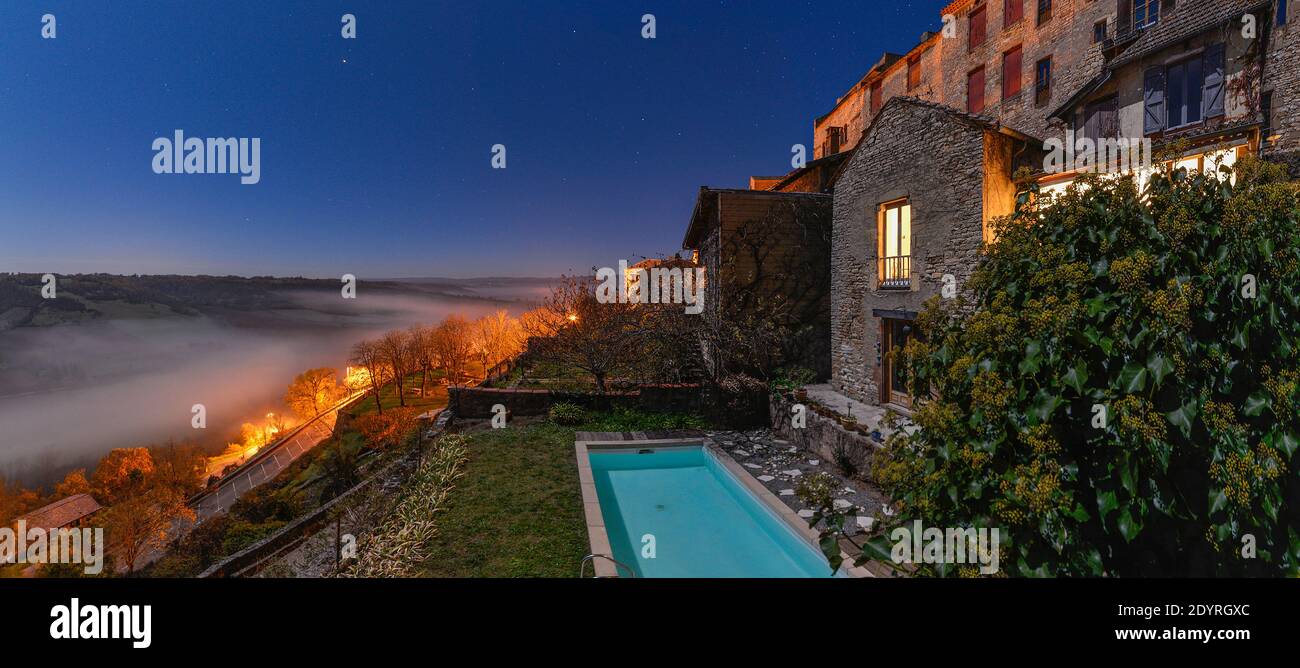 Ein nebeliges französisches Tal, in dem Dorf Cordes-sur-Ciel, das nur bei Mondlicht fotografiert wurde. Stockfoto