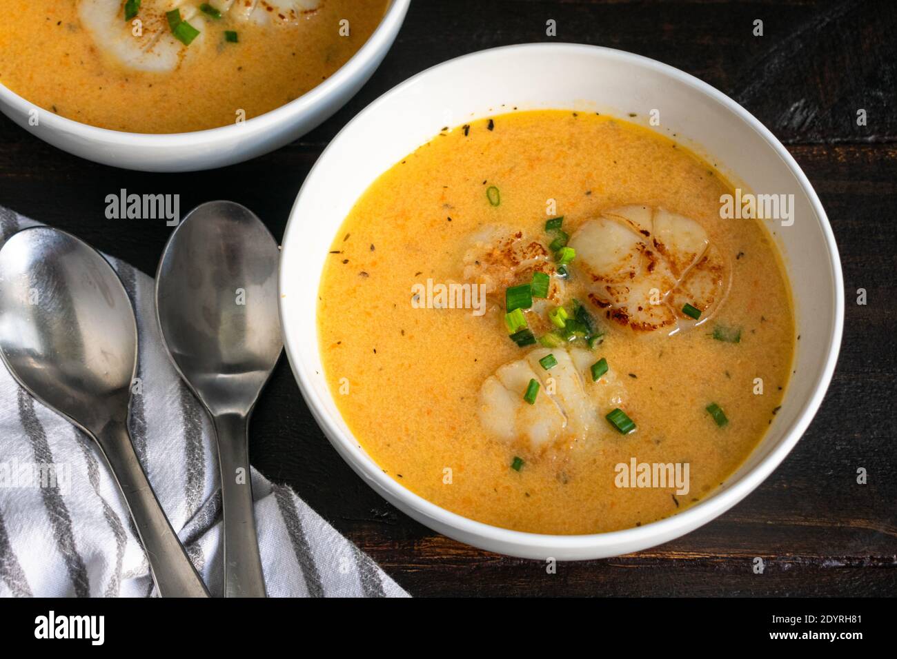 Schalen von Irish Scallop Bisque: Zwei Schalen von Meeresfrüchten Bisque mit Schnittlauch und drei Muscheln gekrönt Stockfoto