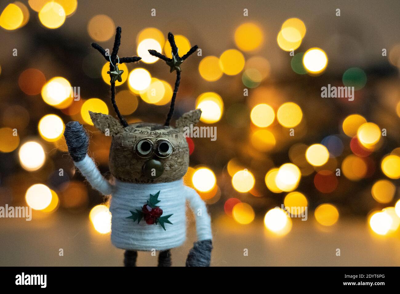 Kreatives Weihnachtskonzept, warmer, einladender, farbenfroher Bokeh-Hintergrund mit einer winkenden recycelten Korkdeko aus Champagner-Kork Stockfoto
