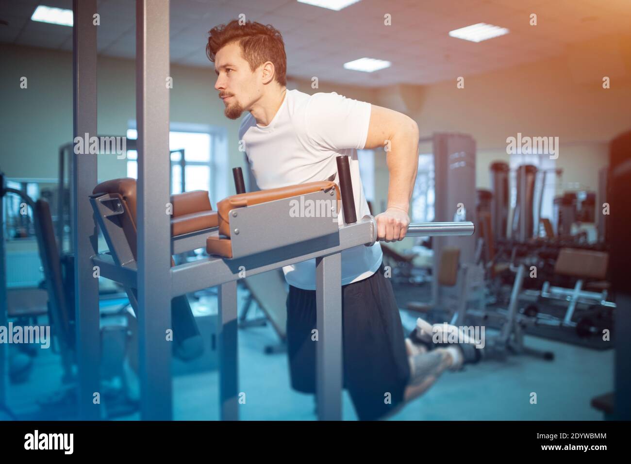 Junge sportliche Mann hat persönliches Training und ziehen auf Bar im Fitnessraum Stockfoto