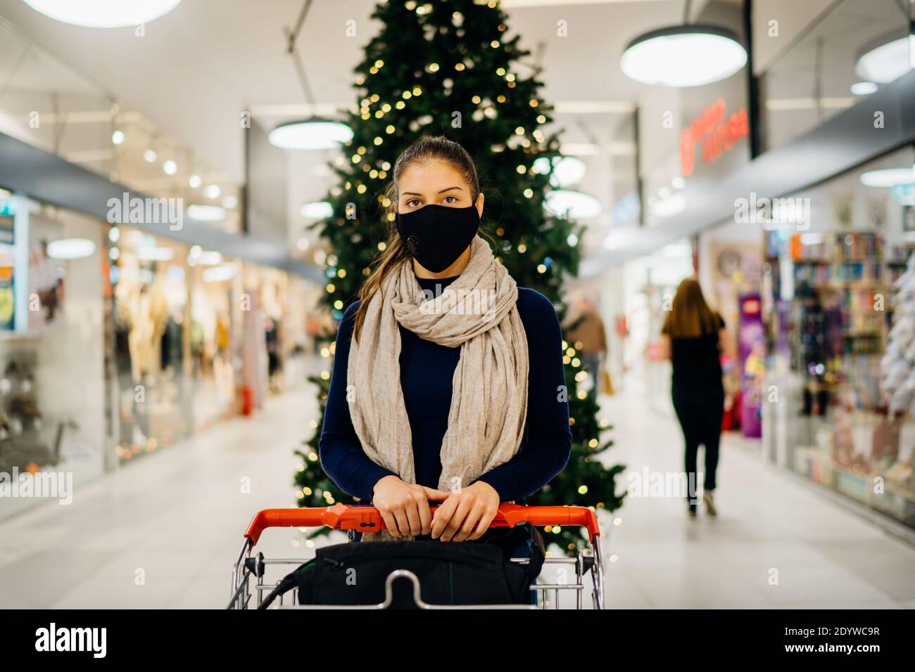 Junge Frau trägt schützende Gesichtsmaske Einkaufen in einer Mall, Kauf Urlaub presents.Holiday Shopping.Christmas Dekoration in Mall.Celebrating Winter Stockfoto