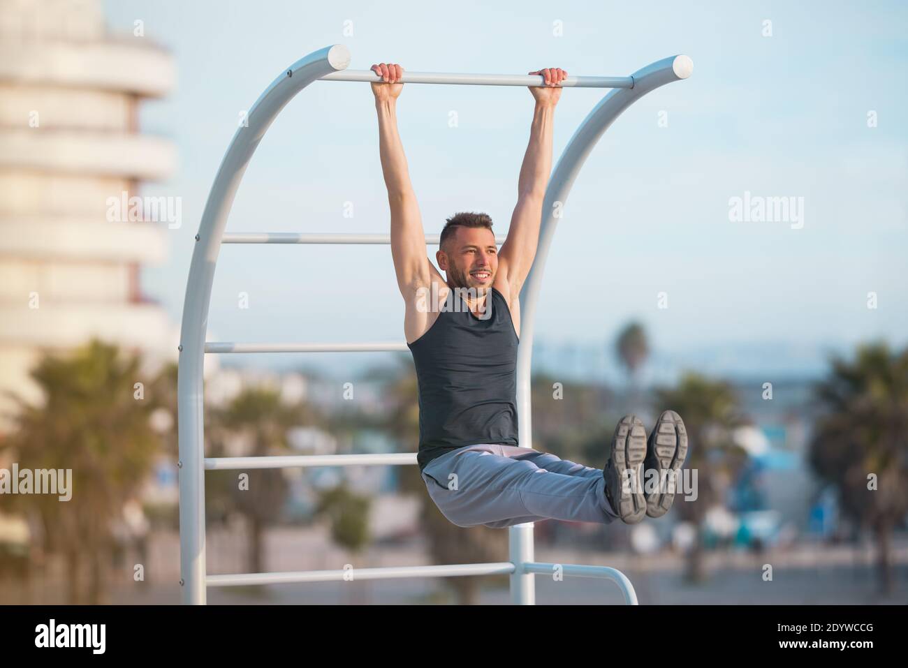 Fit Mann Ausübung seiner bauchmuskeln mit hängenden Bein hebt. Mann macht Pull-ups im Freien Stockfoto