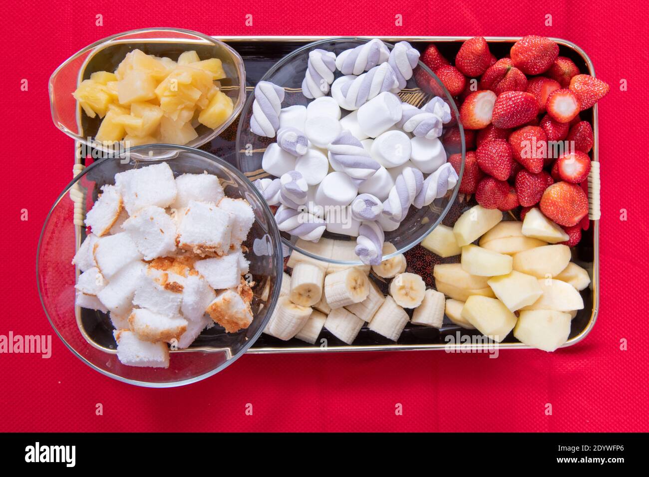 Verschiedene Speisen für Fondue einschließlich Dessert mit Erdbeeren, Äpfeln, Banane, Angel Food Kuchen Ananas und Marshmallows Stockfoto