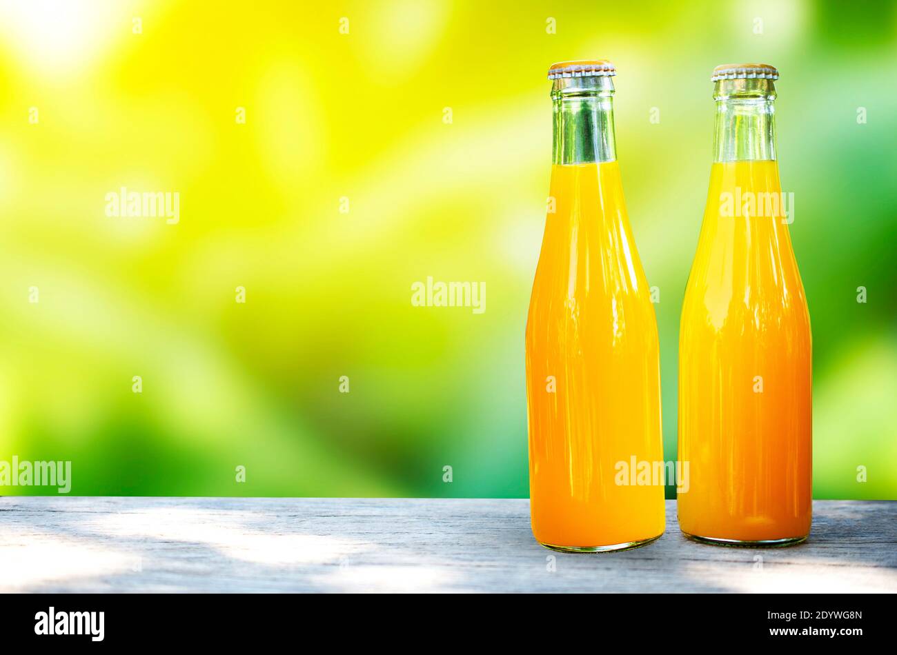 Orangensaft in Glasflaschen verpackt Tischplatte aus Holz und grüne Natur Hintergrund Stockfoto