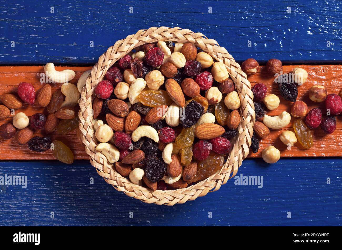 Verschiedene Nüsse und getrocknete Früchte in Schale und in der Nähe auf bunten Holz vorgelegt, Draufsicht Stockfoto