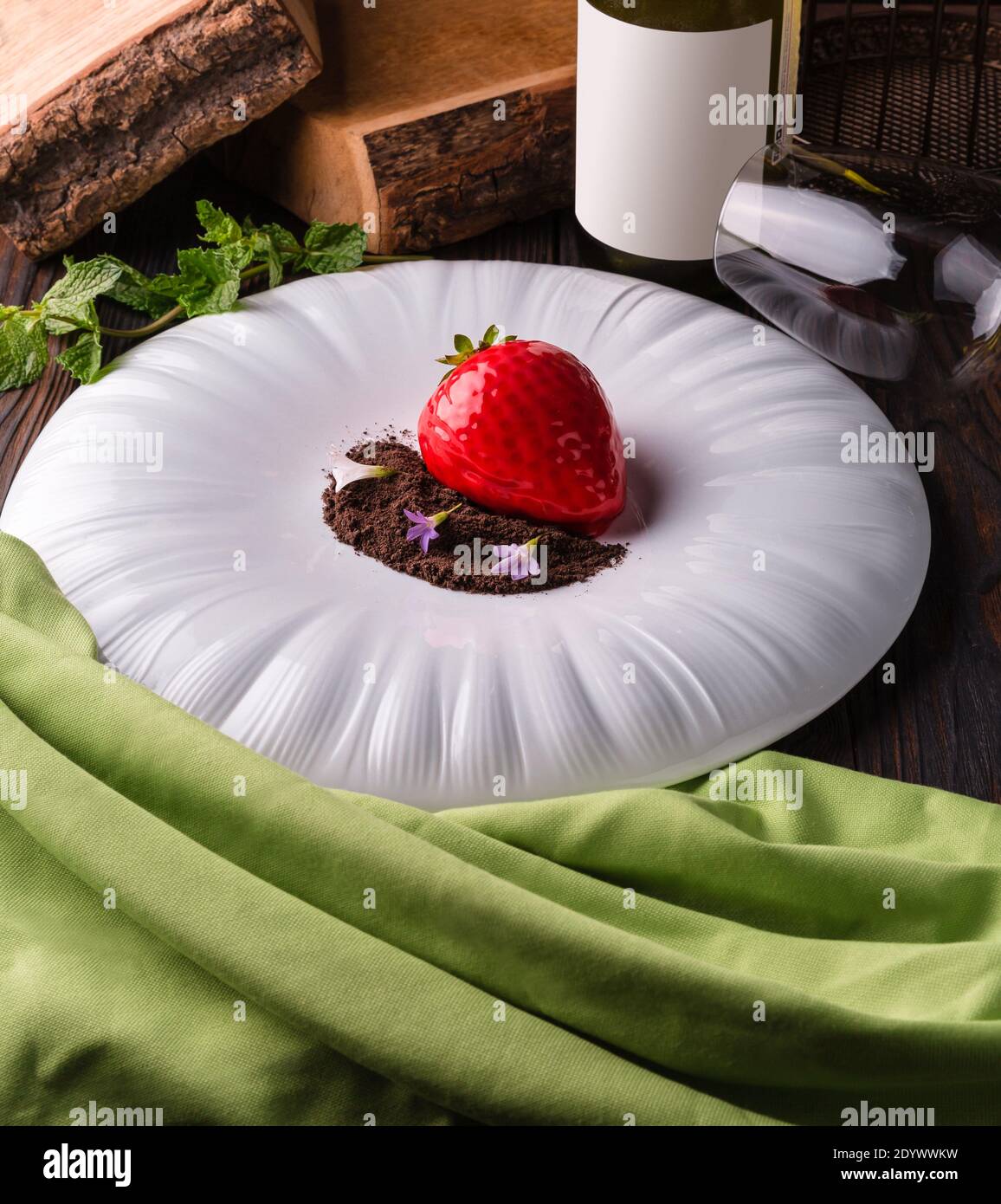 Rote Erdbeere Dessertkuchen mit Schokoladenstückchen und Veilchen auf einem großen weißen Teller. Stockfoto