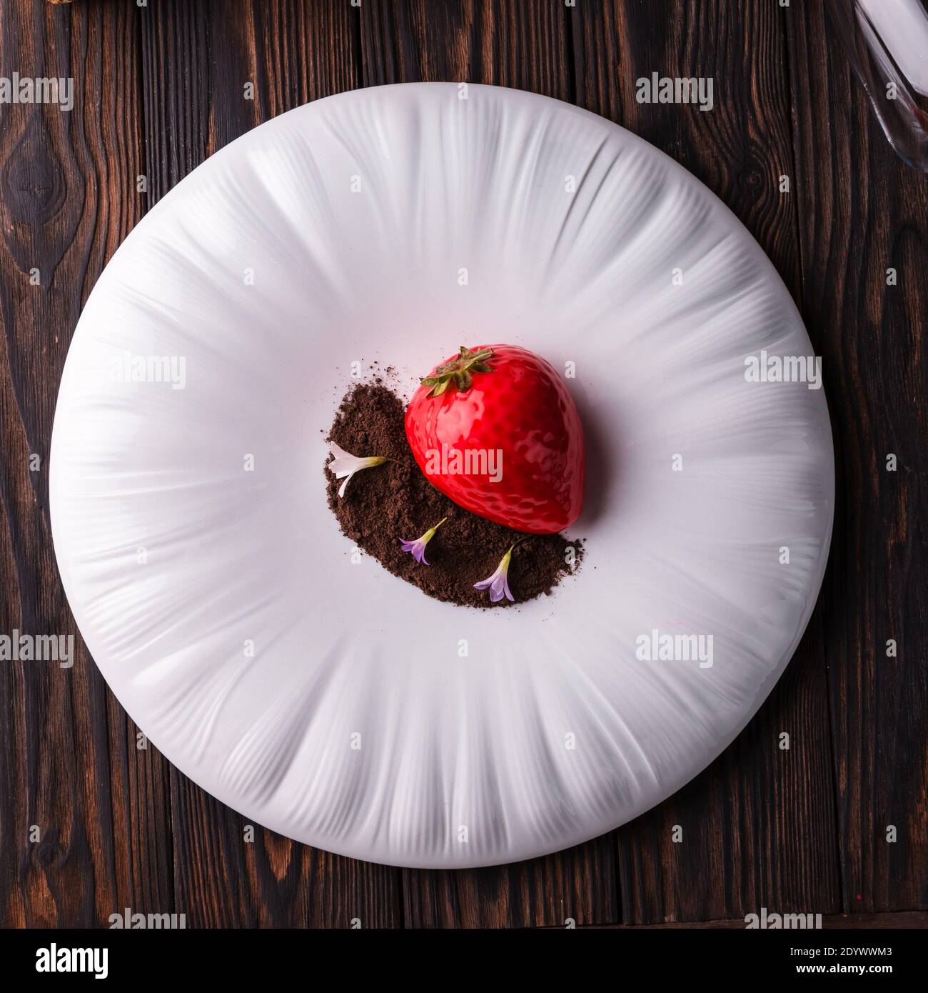 Rote Erdbeere Dessertkuchen mit Schokoladenstückchen und Veilchen auf einem großen weißen Teller. Stockfoto