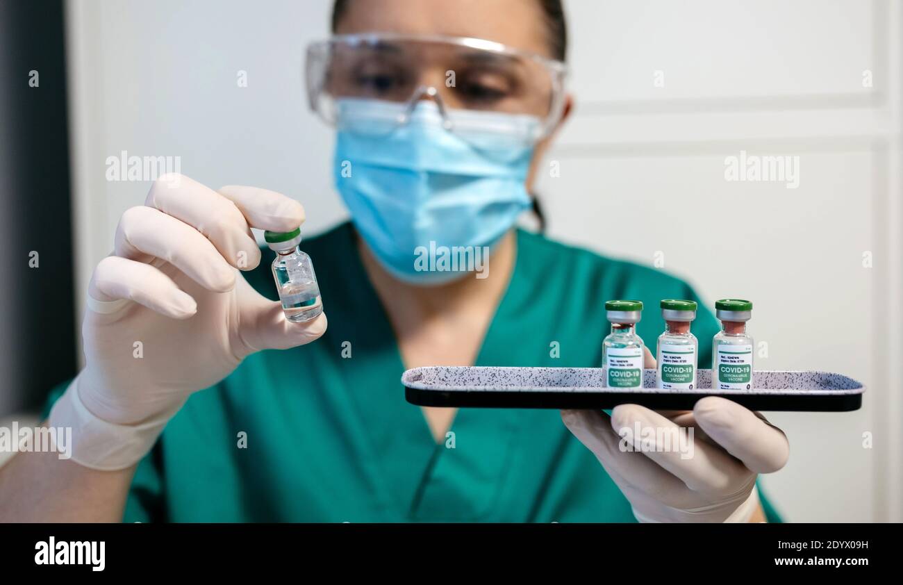 Laborantin, die das Fläschchen des Coronavirus-Impfstoffs untersucht. Stockfoto
