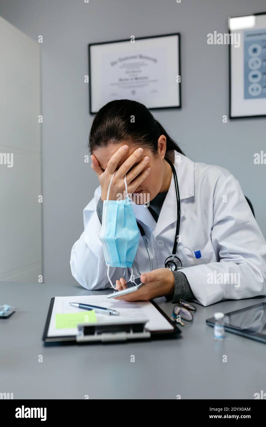 Besorgt weibliche Ärztin mit den Händen auf dem Gesicht Stockfoto
