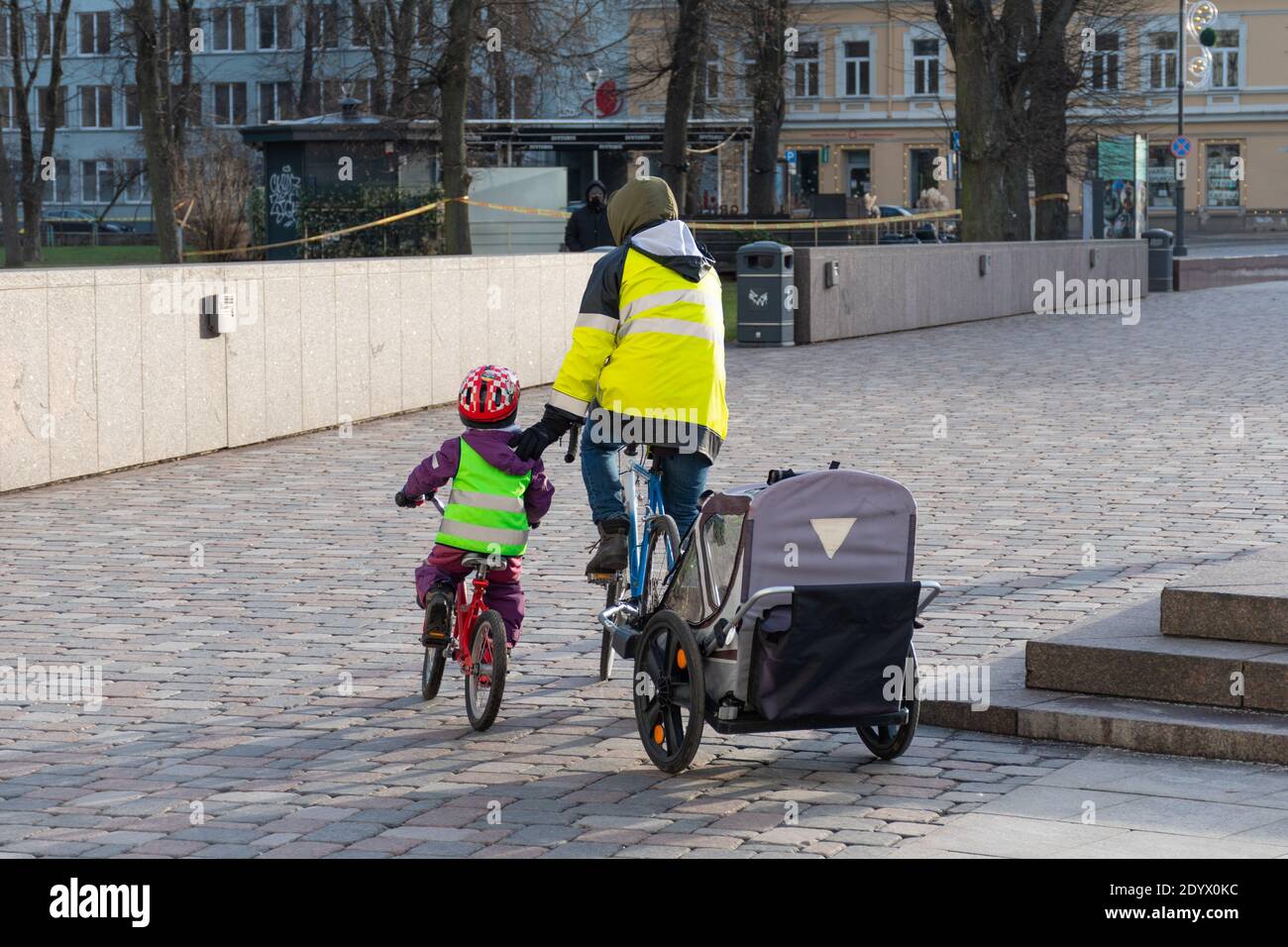 Vater mit Fahrradwagen und Kinder, die während des Covid- oder Coronavirus-Notfalls in der Stadt Rad fahren, nachhaltiges Verkehrskonzept Stockfoto