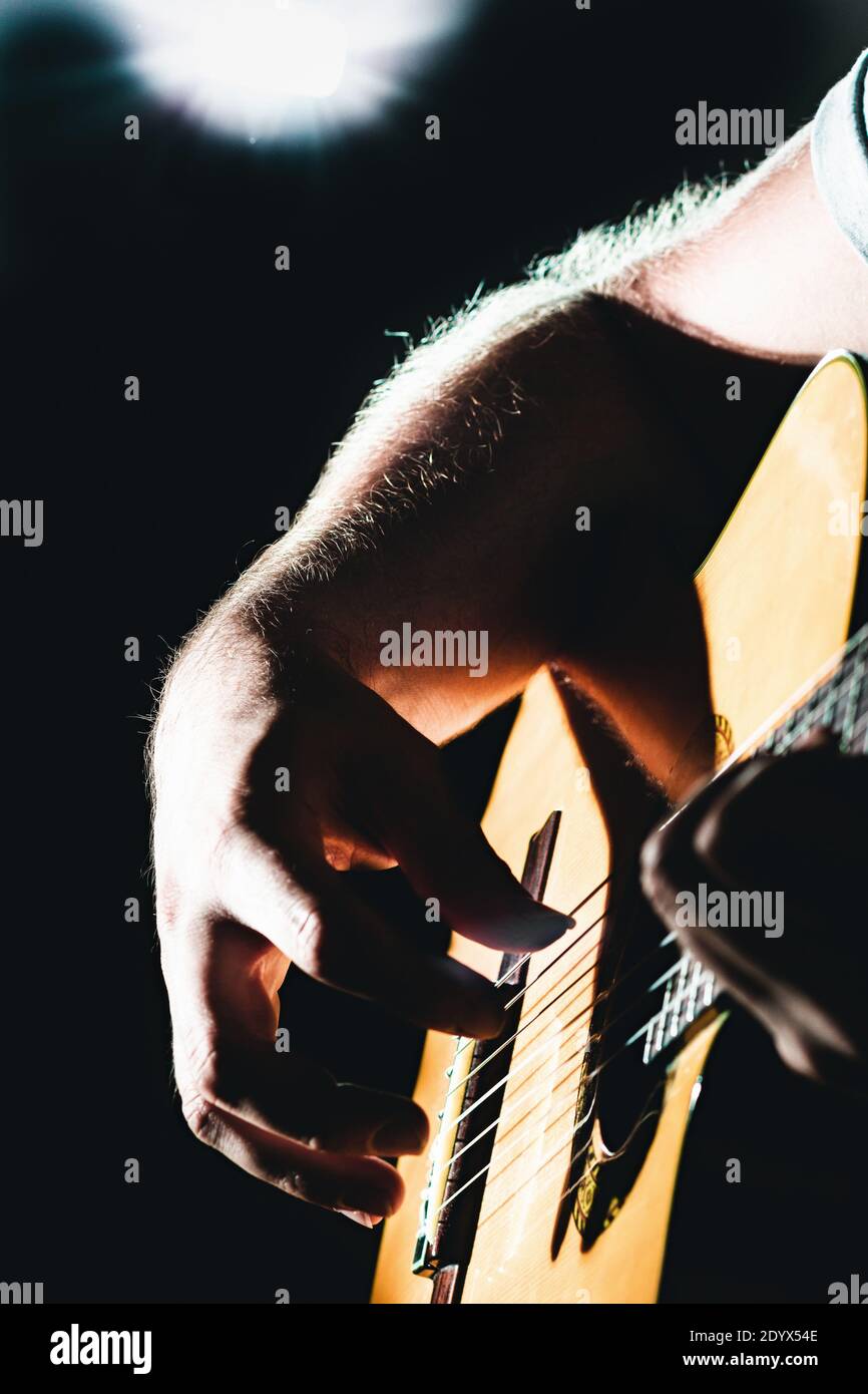 Nahaufnahme der Hände des Mannes, die klassische Gitarre spielen. Musical musikalische Konzertbeleuchtung, vertikal Stockfoto