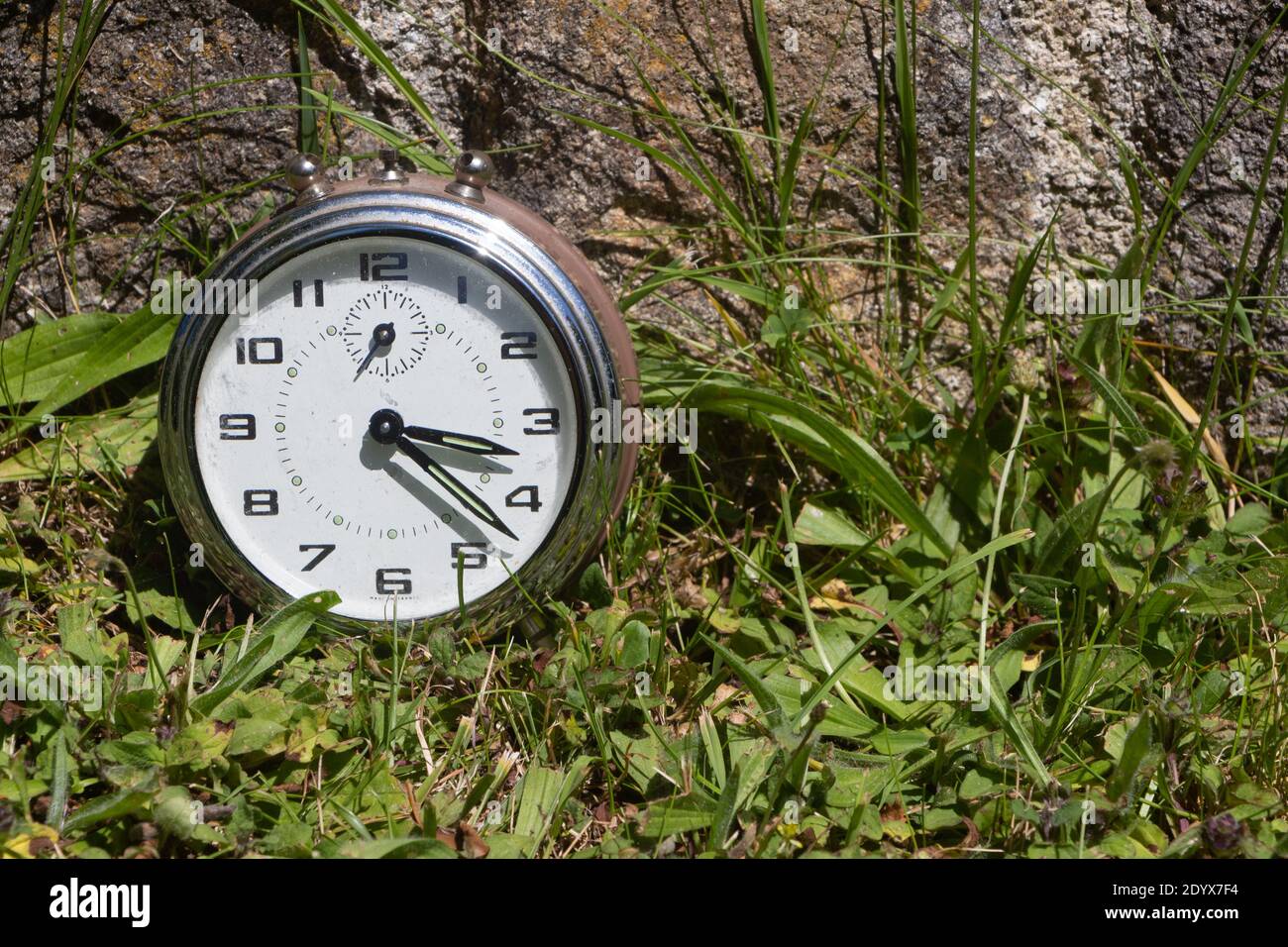 MetallWecker in einem Garten zu symbolisieren es ist Zeit