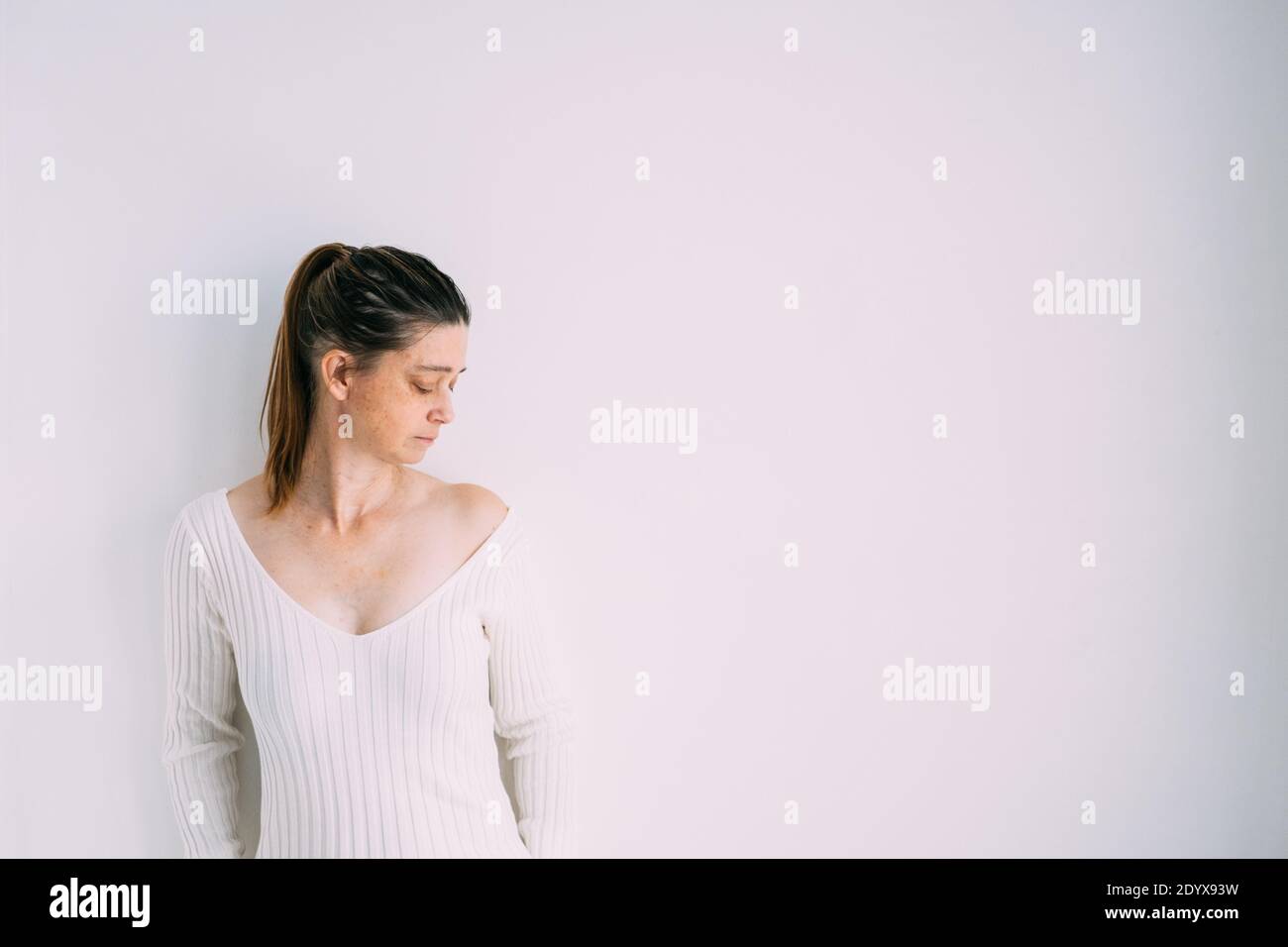 Frau trägt ein langes Rippenstrick Slim Pullover Kleid stehen neben Zu einer weißen Wand Stockfoto