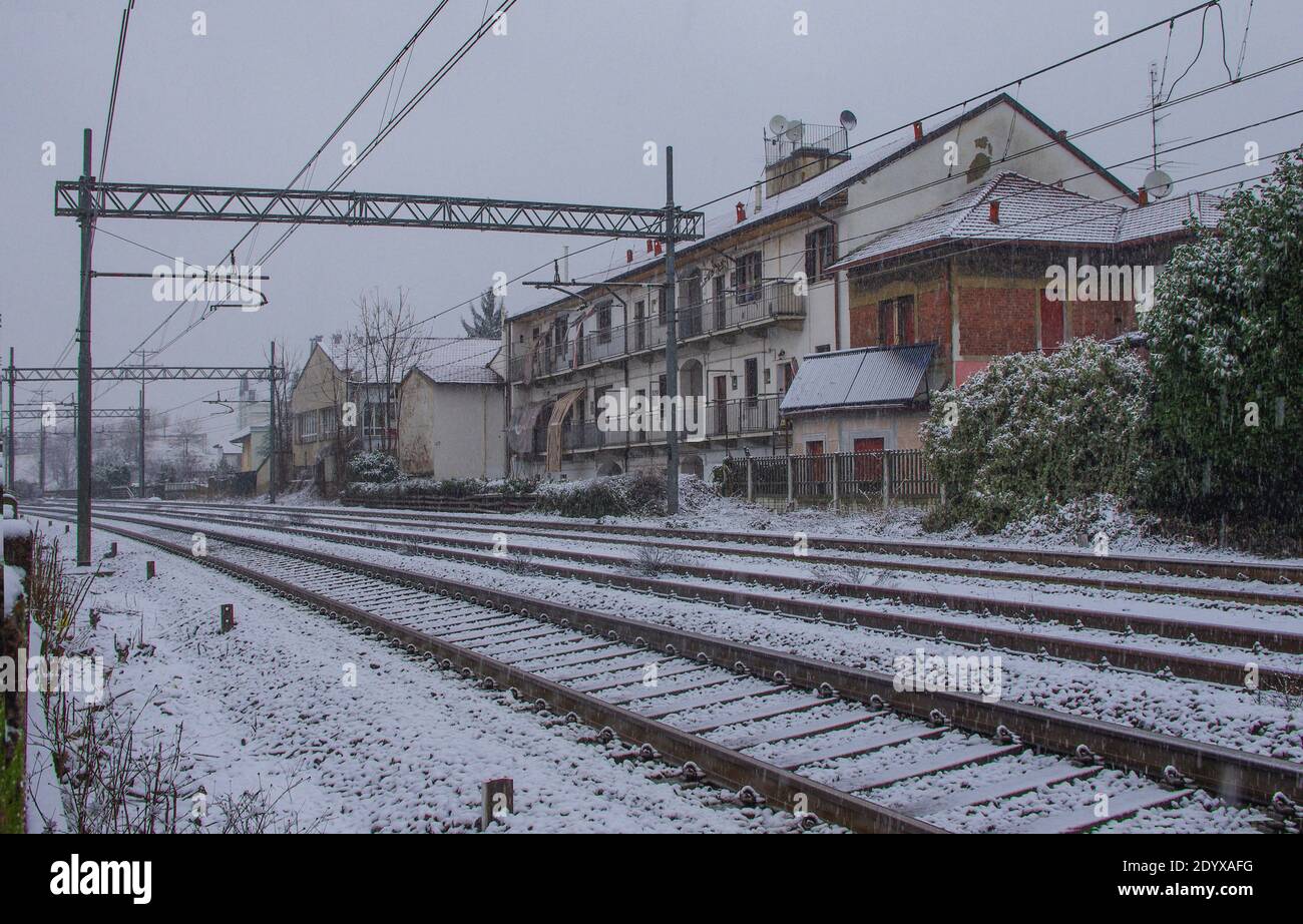 Spuren und alte Häuser entlang der Eisenbahn, die an einem kalten Wintertag von Schnee getüncht ist. Metropolstadt Mailand, Lombardei, Italien. Stockfoto