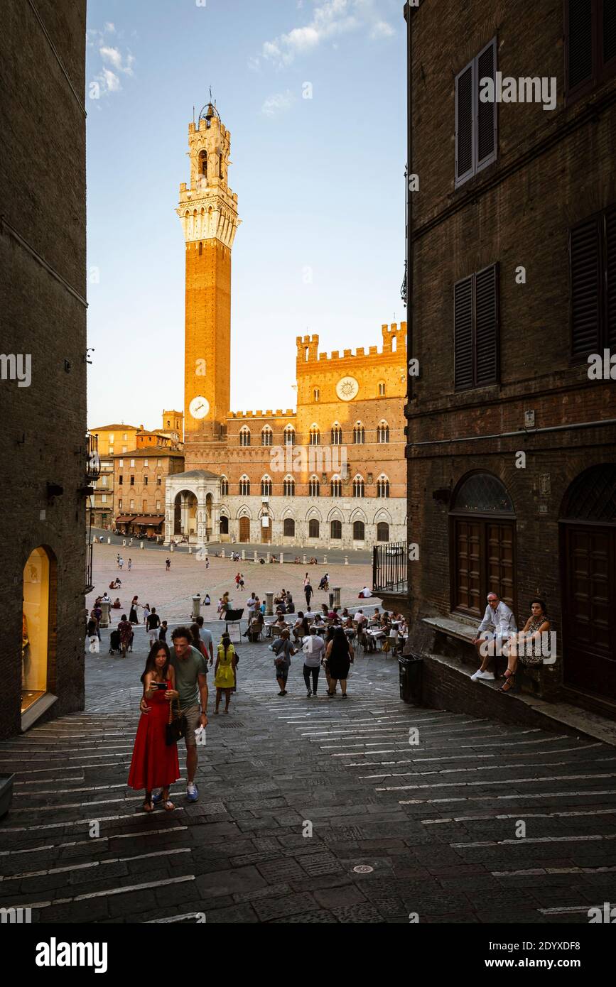 Junges Paar, das ein Selfie-Foto vor dem Hintergrund des Torre del Mangia, Palazzo Publico auf der Piazza del Campo, Siena, Toskana, Italien macht Stockfoto