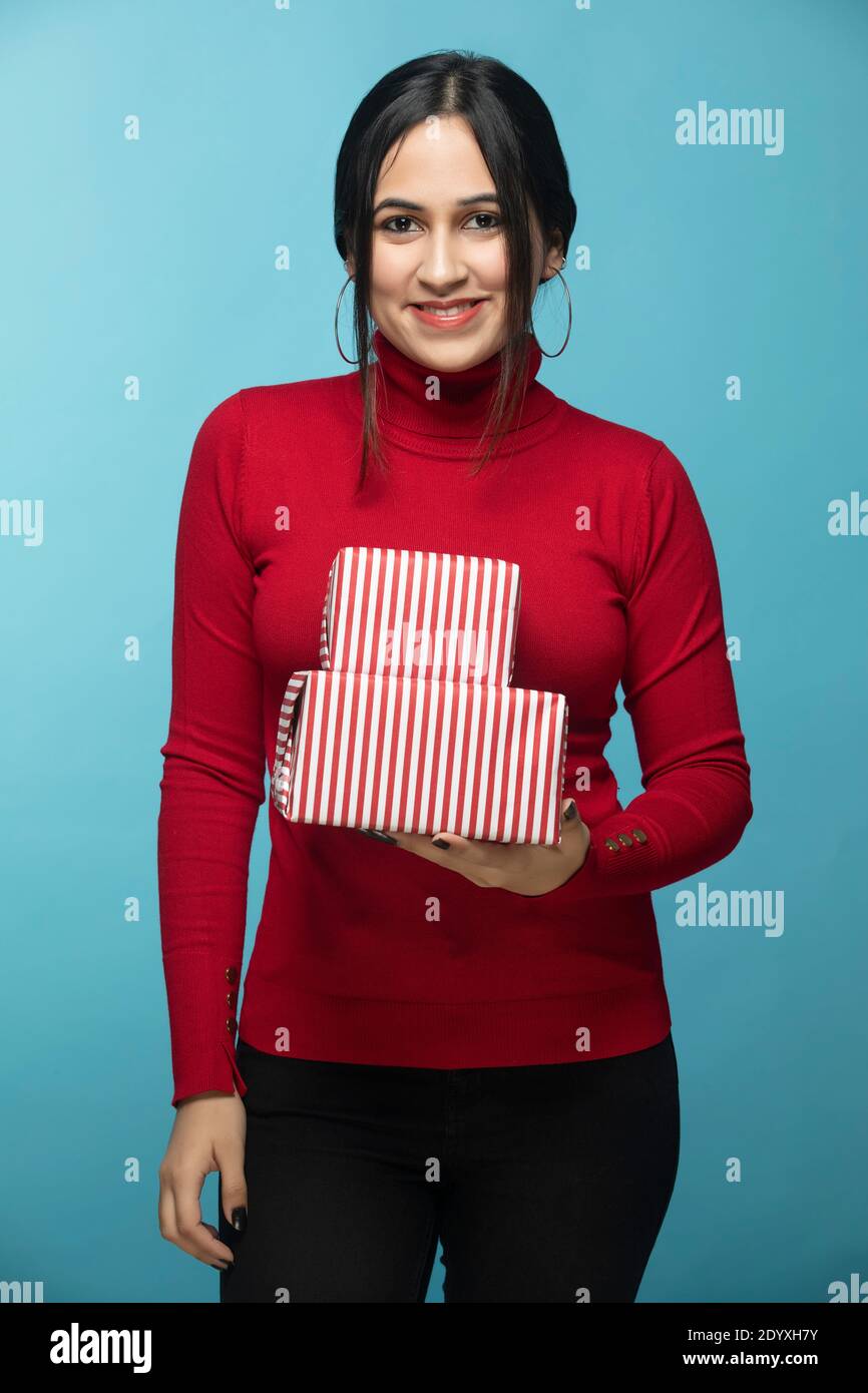 Porträt einer jungen Frau trägt roten Sweatshirt und halten Geschenk Box in der Hand Stockfoto