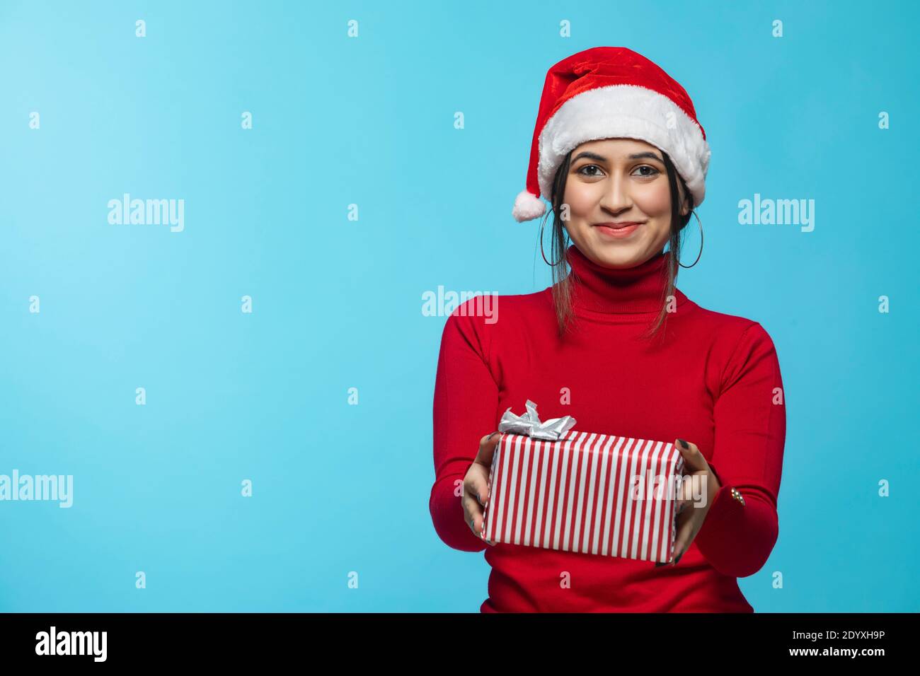 Porträt einer lächelnden jungen Frau, die Weihnachtsmütze trägt und hält Geschenkbox Stockfoto