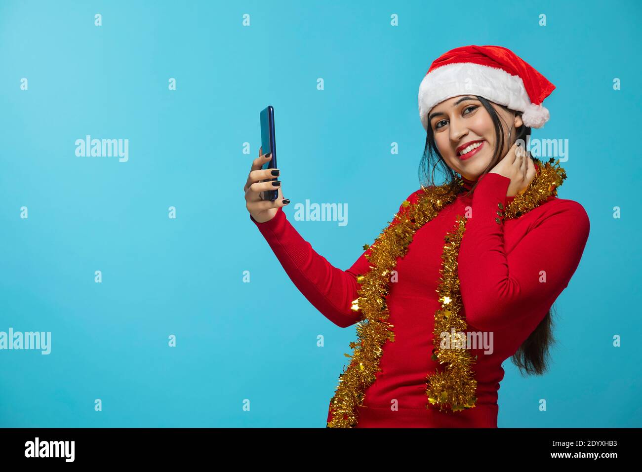 Ein Porträt einer Frau mit Weihnachtsmütze, die mobil hält Telefon Stockfoto
