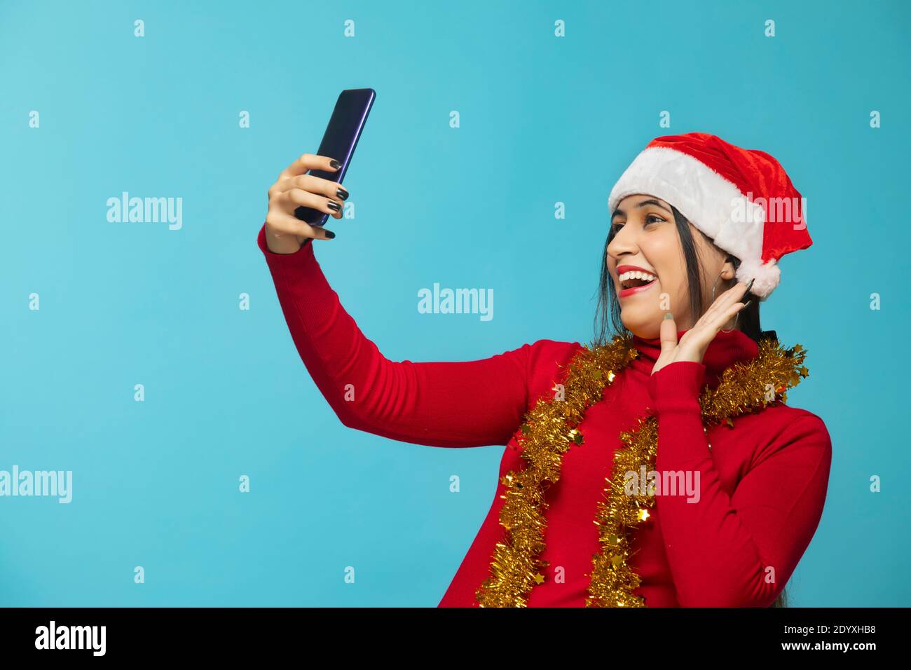 Frau, die Selfie mit Handy trägt Weihnachtshut Stockfoto