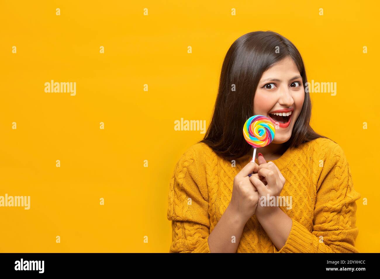 Junge Frau lacht vor Aufregung mit einem Lollipop Stockfoto