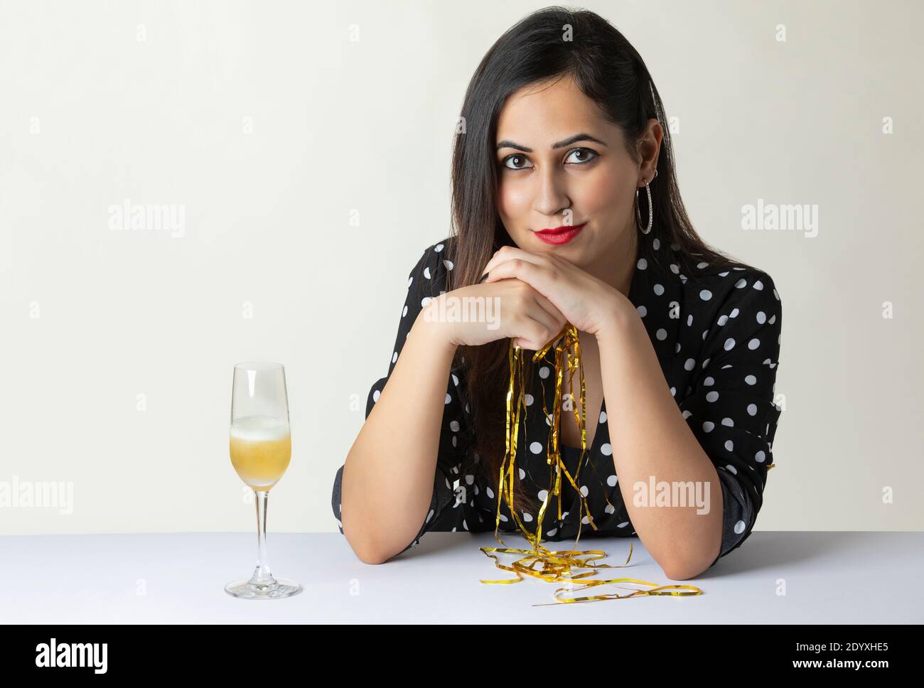 Junge Frau sitzt am Tisch mit Champagner Stockfoto